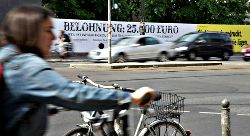 Straßenszene, im Hintergrund Plakat: »Belohnung 25 000 Euro«.