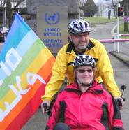 Brigitte und Wolfgang auf ihrem Tandem mit Regenbogen-Friedensfahne.